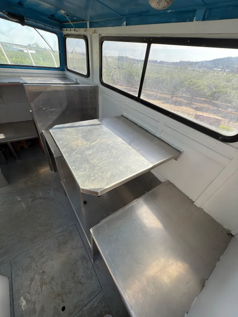 Slide: The Image of 1975 Monark 30 Fishing Boat interior with metal seating and table, featuring large windows. - 18