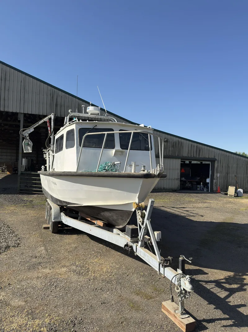 Slide: The Image of 1975 Monark 30 Fishing Boat on trailer, parked outdoors near a wooden building. - 28