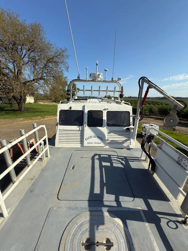 Slide: The Image of 1975 Monark 30 Fishing Boat on land, showcasing deck and equipment under clear blue sky. - 4