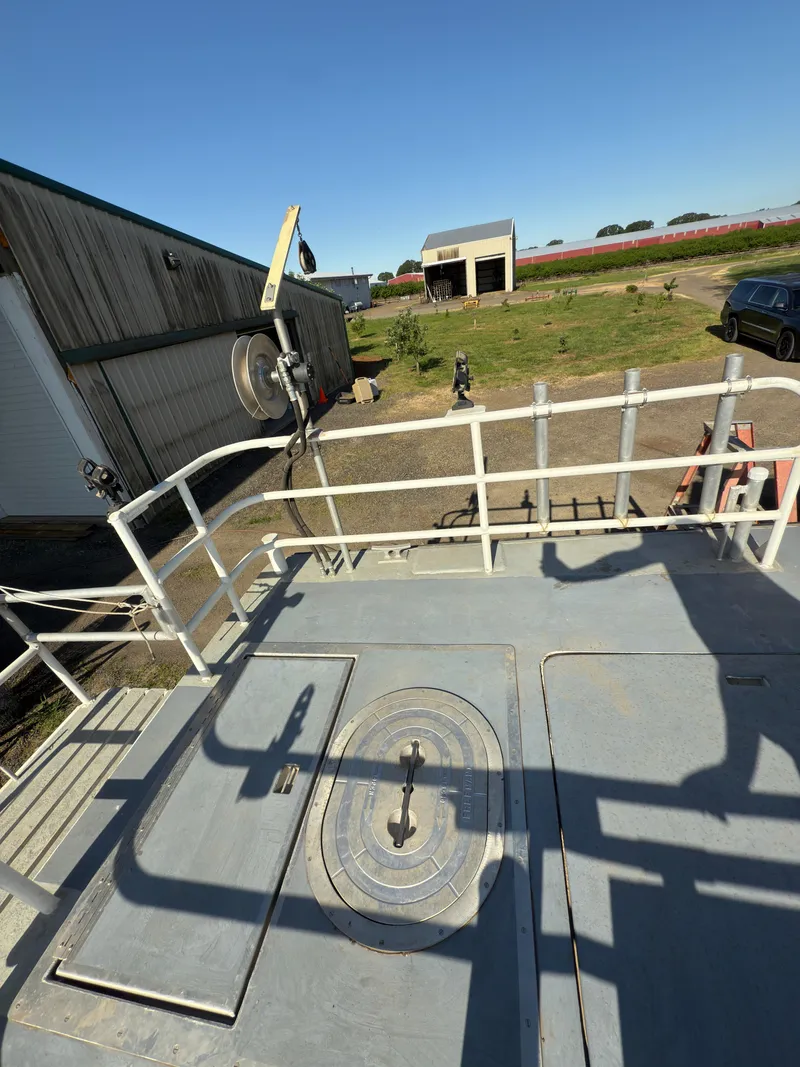 Slide: The Image of 1975 Monark 30 Fishing Boat deck with railing, docked near a rural building. - 8
