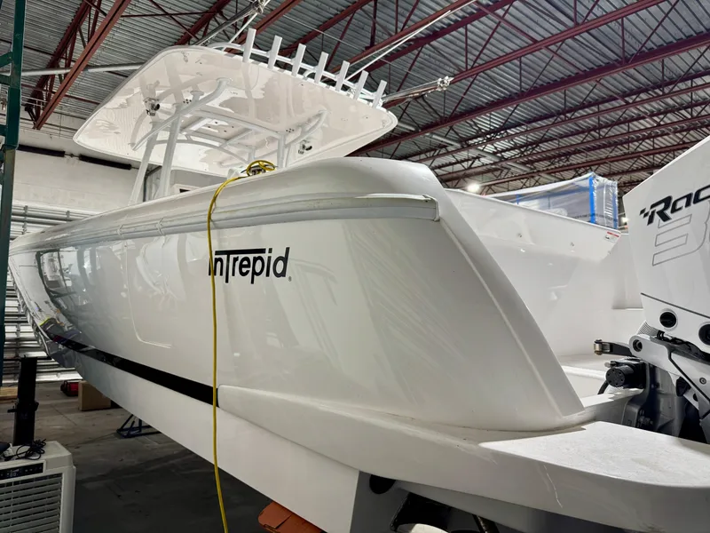 Slide: The Image of 2020 Intrepid 407 Nomad FE boat in a warehouse, showcasing sleek design and powerful engine. - 2