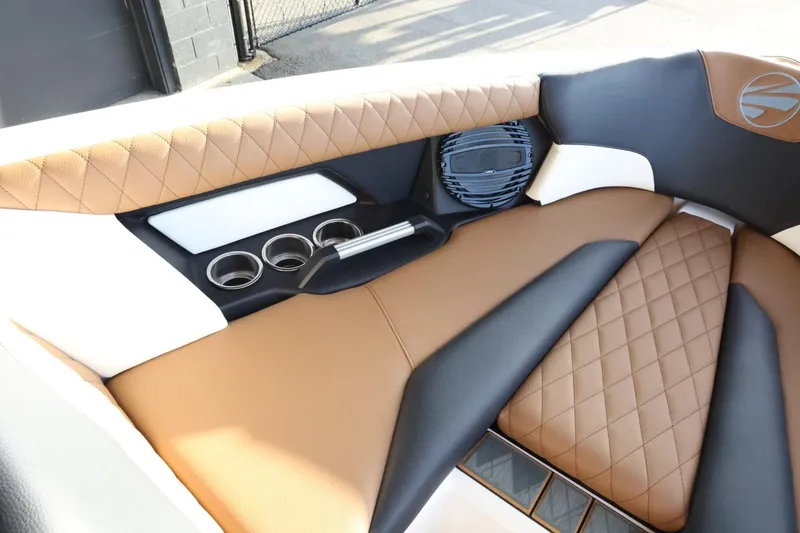 Slide: The Image of 2025 Tigé Z3 boat interior with brown and black quilted seats, cup holders, and speaker. - 18