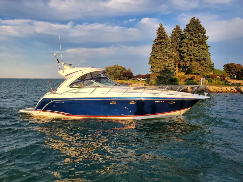 Slide: The Image of 2009 Formula 40 PC yacht on serene water near a lush, tree-lined shore. - 0