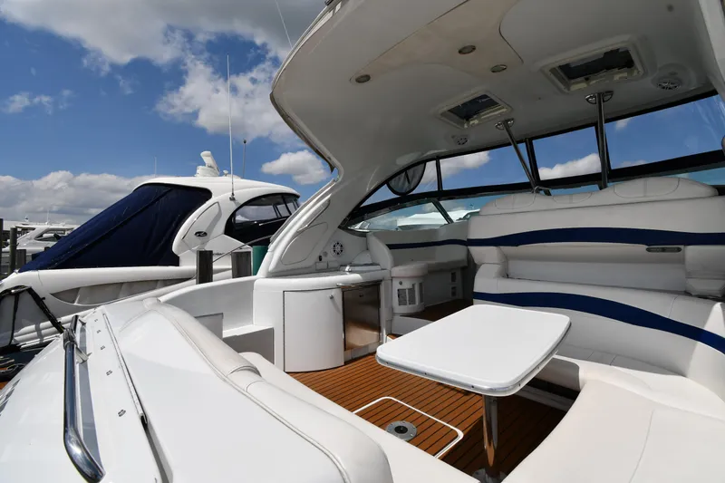 Slide: The Image of 2009 Formula 40 PC yacht interior with white seating, table, and wood flooring under a blue sky. - 23