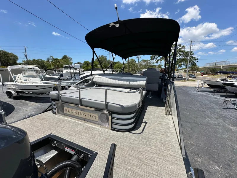 Slide: The Image of 2021 Bennington LX 24 Stern Lounge pontoon boat with canopy, docked under a sunny sky. - 6
