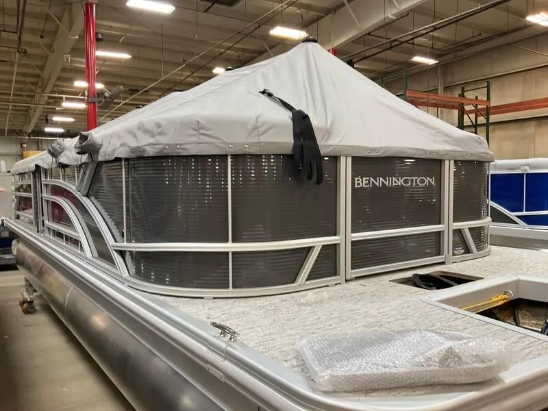 Slide: The Image of 2025 Bennington 23SSR-SPS pontoon boat with cover in a warehouse setting. - 16