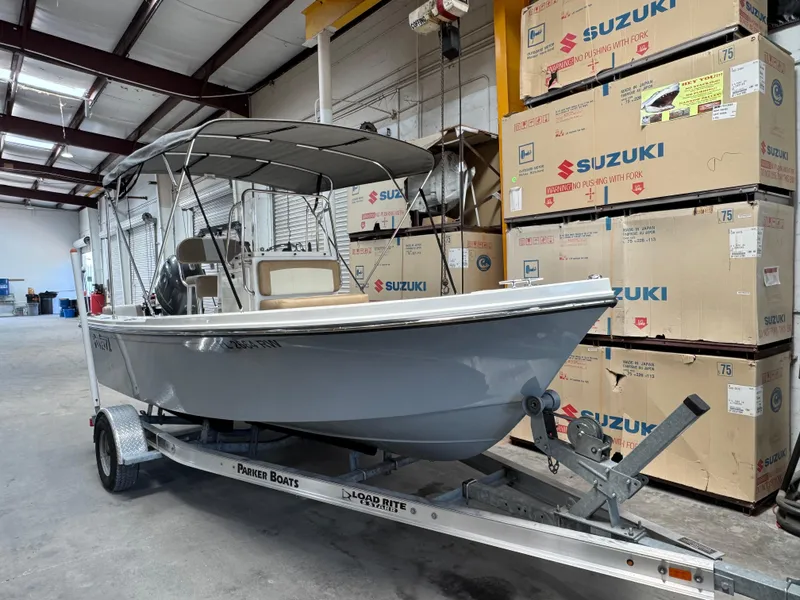 Slide: The Image of 2019 Parker 1801 CC boat on trailer in warehouse, surrounded by Suzuki boxes. - 1