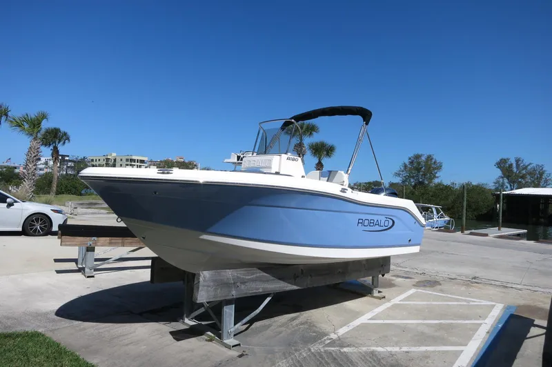 Slide: The Image of 2025 Robalo R180 Center Console boat on display under clear blue sky. - 12