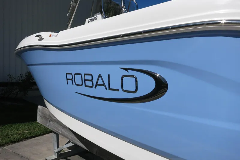 Slide: The Image of 2025 Robalo R180 Center Console boat with blue hull and sleek design. - 19