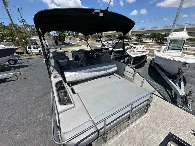 Slide: The Image of 2021 Bennington LX 24 Swingback pontoon boat with canopy, docked under a clear blue sky. - 8