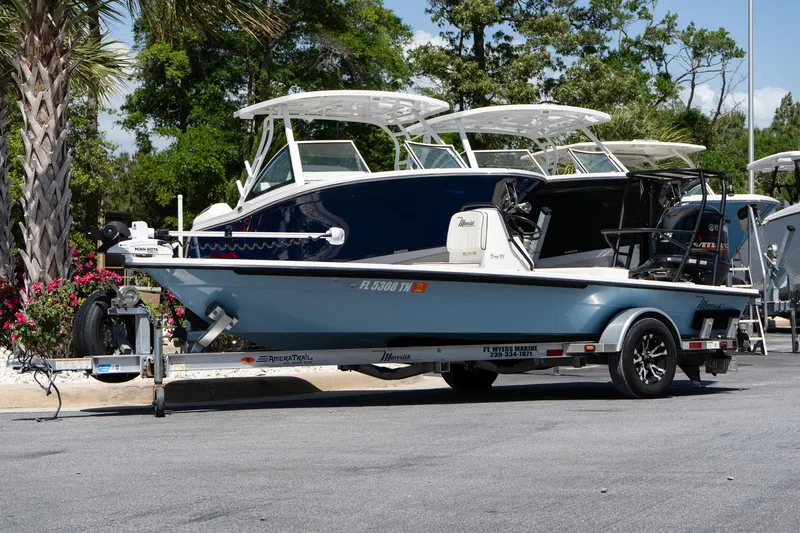 Slide: The Image of 2023 Maverick 18 HPX-V boat on trailer, parked outdoors with trees in background. - 8