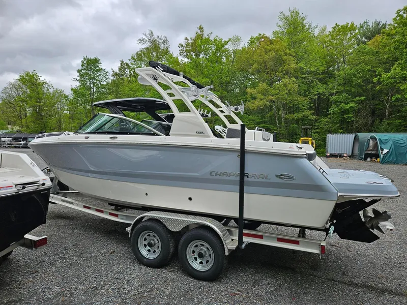 Slide: The Image of 2025 Chaparral 247 SSX boat on trailer, parked outdoors with trees in background. - 2