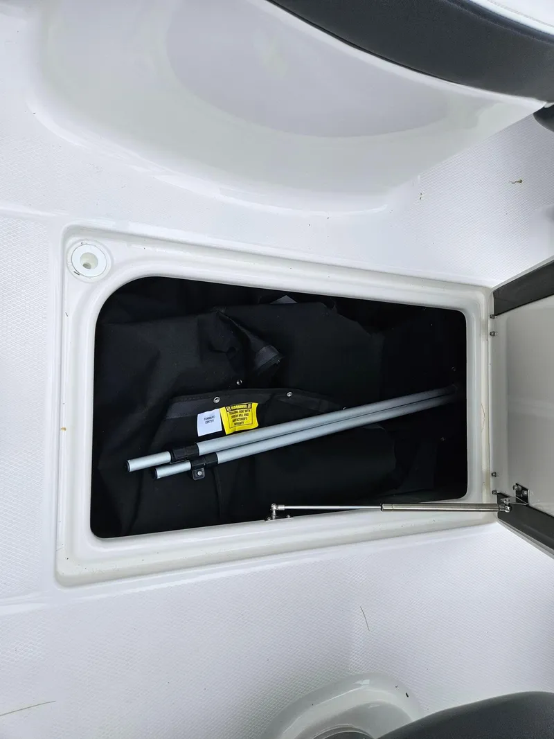 Slide: The Image of Storage compartment in 2025 Chaparral 247 SSX boat, containing metal rods and equipment. - 39