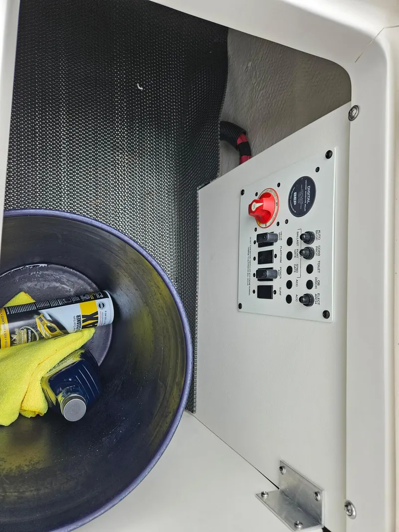 Slide: The Image of 2025 Chaparral 247 SSX boat storage compartment with control panel and cleaning supplies. - 45