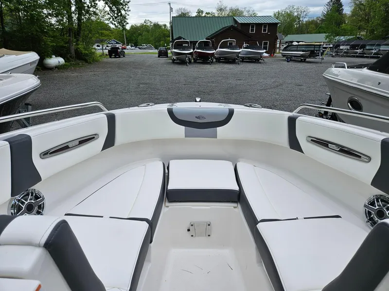 Slide: The Image of 2025 Chaparral 247 SSX boat interior with white and gray seating in a marina setting. - 7