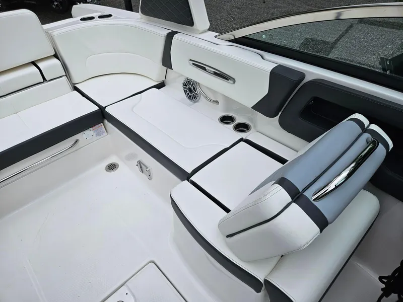 Slide: The Image of 2025 Chaparral 247 SSX boat interior with white seating, cup holders, and speaker. - 9