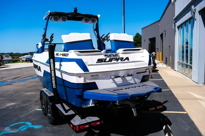 Slide: The Image of 2023 Supra SL boat on trailer, parked outside a building. - 4