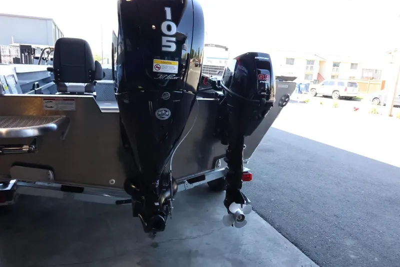 Slide: The Image of 2025 Thunder Jet 209 Rush OT boat with dual outboard motors in a parking area. - 8