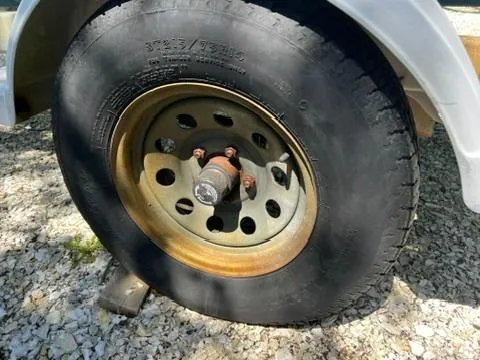 Slide: The Image of Trailer wheel of a 2001 Aquasport 200 Osprey on gravel surface. - 19