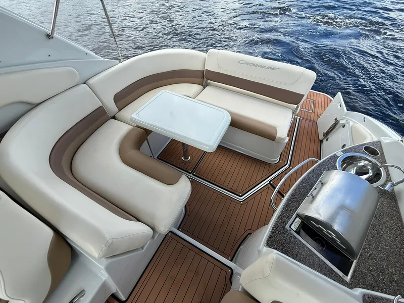 Slide: The Image of 2019 Crownline 350 SY boat interior with seating, table, and grill on teak deck. - 16