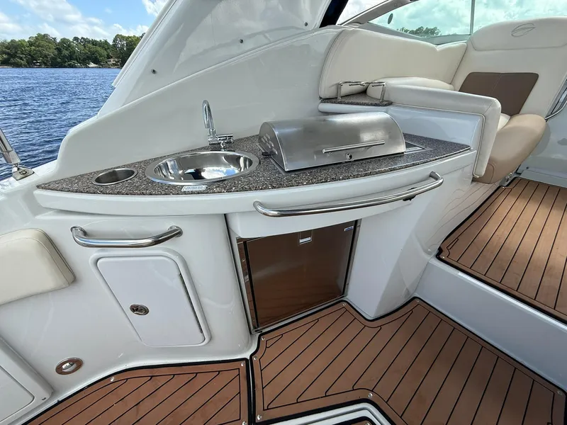 Slide: The Image of Luxury 2019 Crownline 350 SY yacht interior with kitchenette and seating, overlooking serene water. - 17