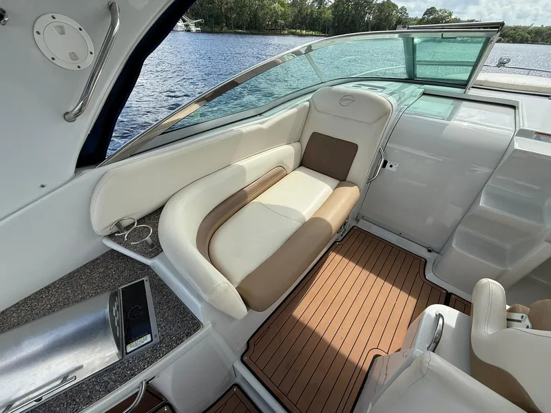 Slide: The Image of 2019 Crownline 350 SY yacht interior with cushioned seating and wooden flooring by the water. - 18