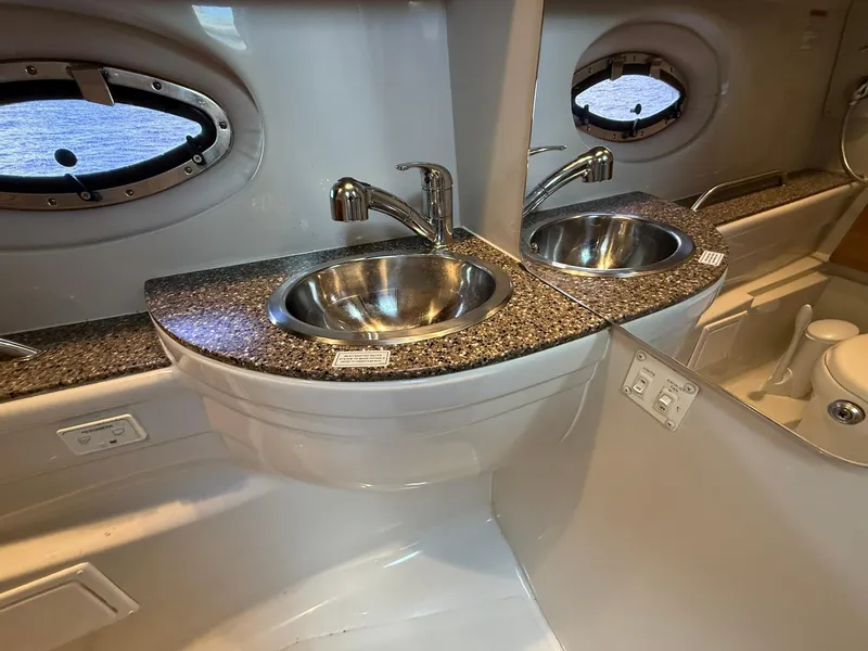 Slide: The Image of 2019 Crownline 350 SY bathroom with dual sinks, granite countertop, and porthole windows. - 40