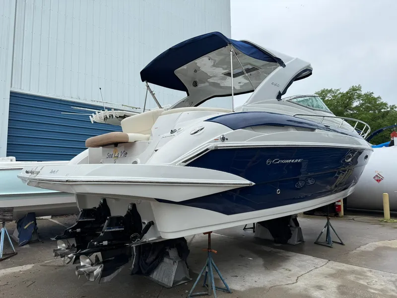 Slide: The Image of 2019 Crownline 350 SY boat on stands, blue and white exterior, docked outdoors. - 9