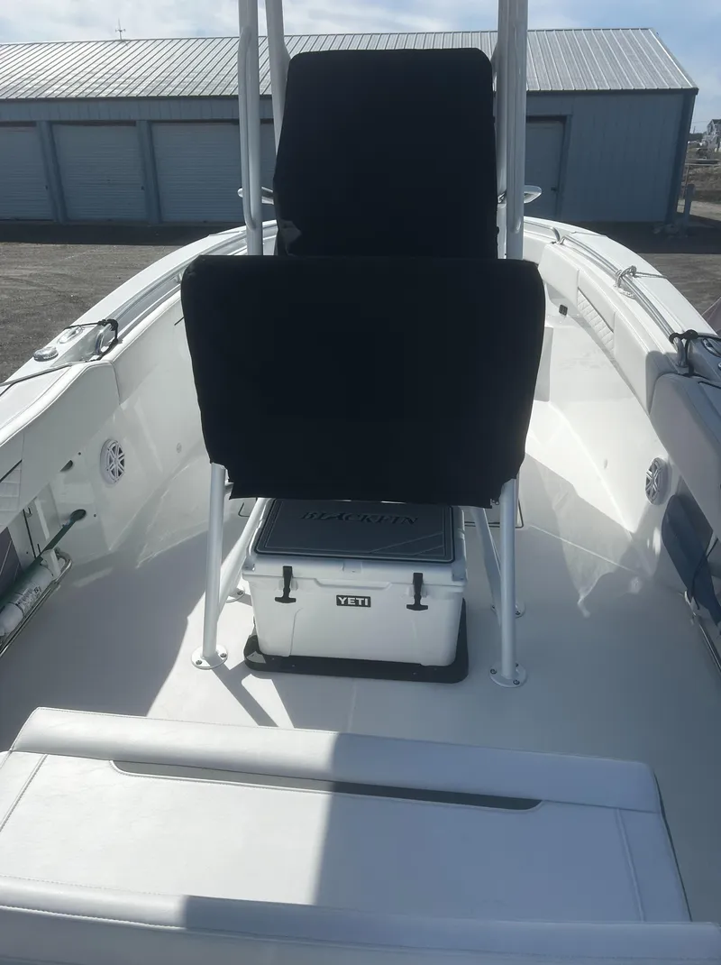 Slide: The Image of 2022 Blackfin 222 CC boat interior with seating and storage, docked near storage units. - 13