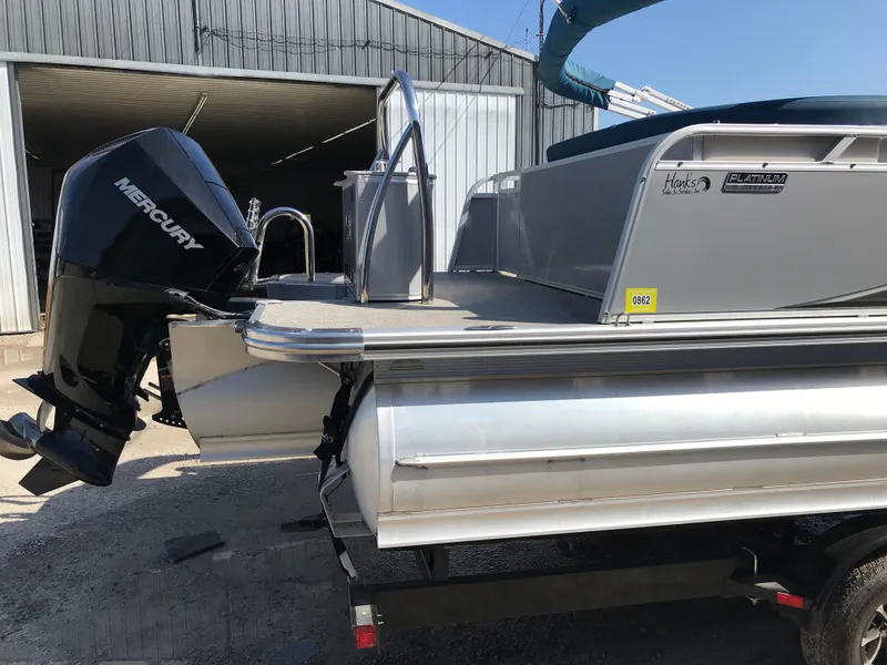 Slide: The Image of 2023 Avalon LSZ Elite Windshield pontoon boat with Mercury outboard motor, parked near a shed. - 10