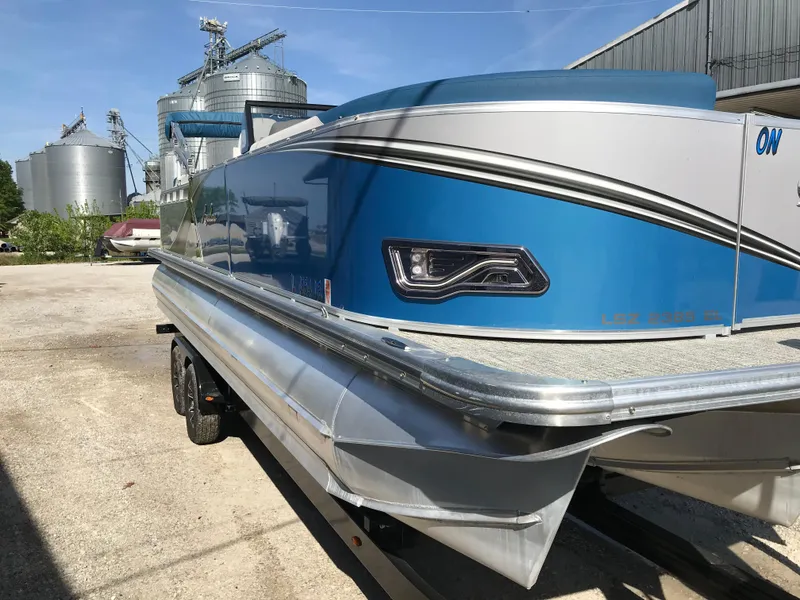 Slide: The Image of 2023 Avalon LSZ Elite Windshield pontoon boat with blue accents, parked outdoors. - 15