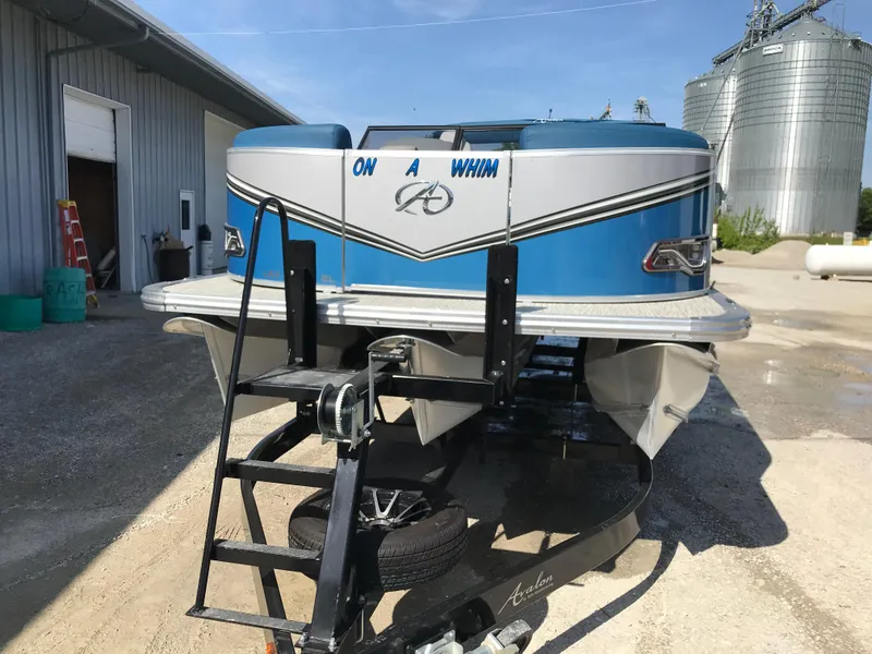 Slide: The Image of 2023 Avalon LSZ Elite Windshield pontoon boat on trailer, labeled "On A Whim," parked outdoors. - 18