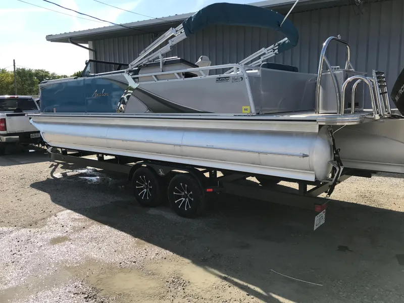 Slide: The Image of 2023 Avalon LSZ Elite Windshield pontoon boat on trailer, parked outdoors. - 4
