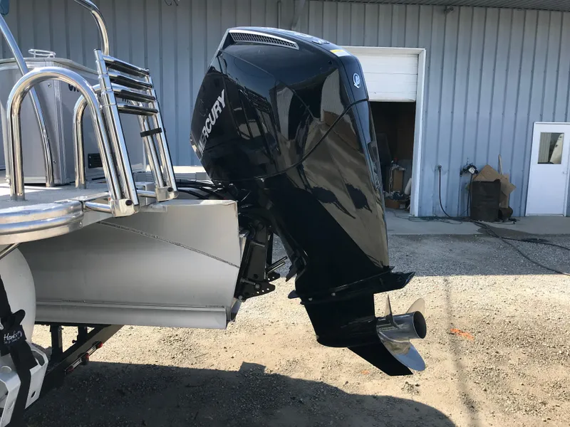 Slide: The Image of 2023 Avalon LSZ Elite Windshield boat with Mercury outboard motor in a yard. - 6