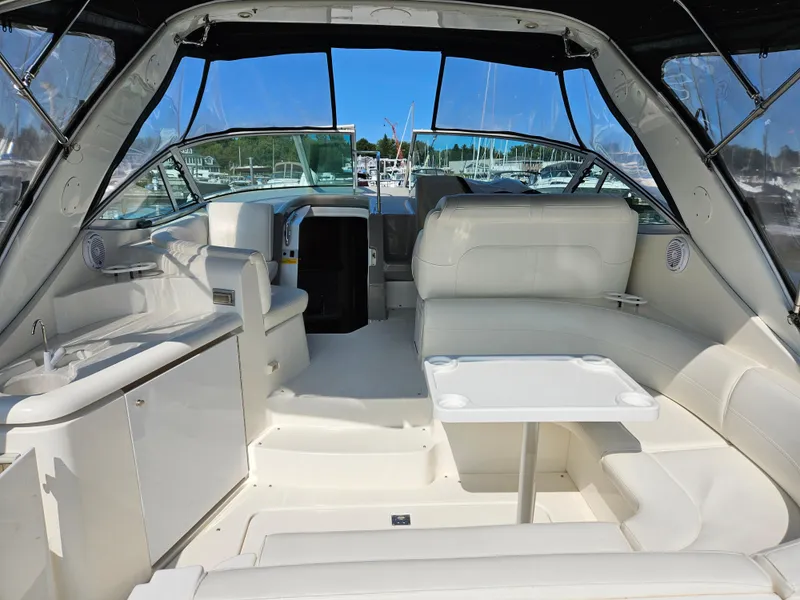 Slide: The Image of 2004 Cruisers Yachts 340 Express interior with white seating and table, docked at marina. - 13