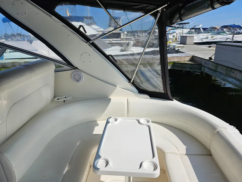 Slide: The Image of 2004 Cruisers Yachts 340 Express interior with white seating and table, docked at marina. - 14