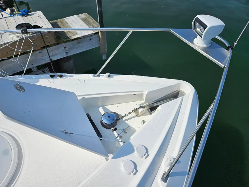 Slide: The Image of 2004 Cruisers Yachts 340 Express bow with anchor and railing, docked by wooden pier. - 23