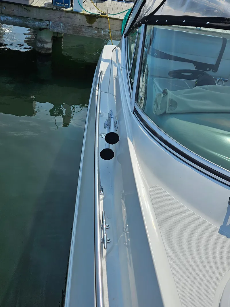 Slide: The Image of 2004 Cruisers Yachts 340 Express, sleek white exterior, docked in calm waters. - 24