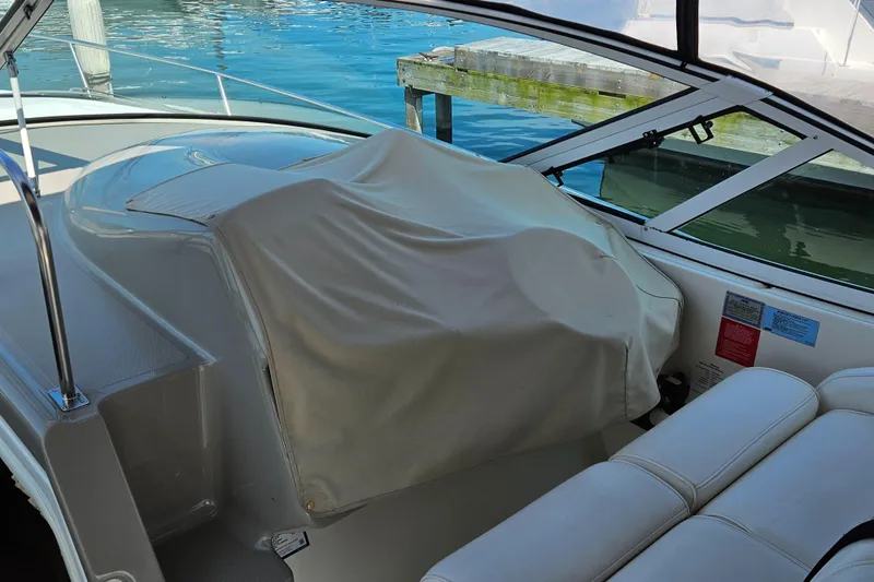Slide: The Image of 2004 Cruisers Yachts 340 Express interior with covered helm, docked by clear blue water. - 26