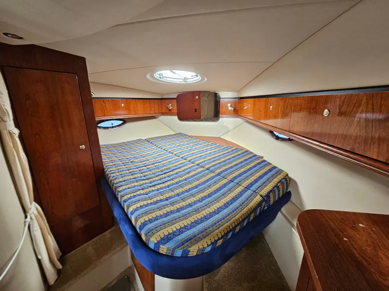 Slide: The Image of 2004 Cruisers Yachts 340 Express cabin with striped bedding and wooden interior. - 28
