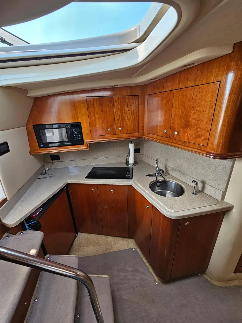 Slide: The Image of 2004 Cruisers Yachts 340 Express kitchen with wood cabinets, sink, and microwave. - 33