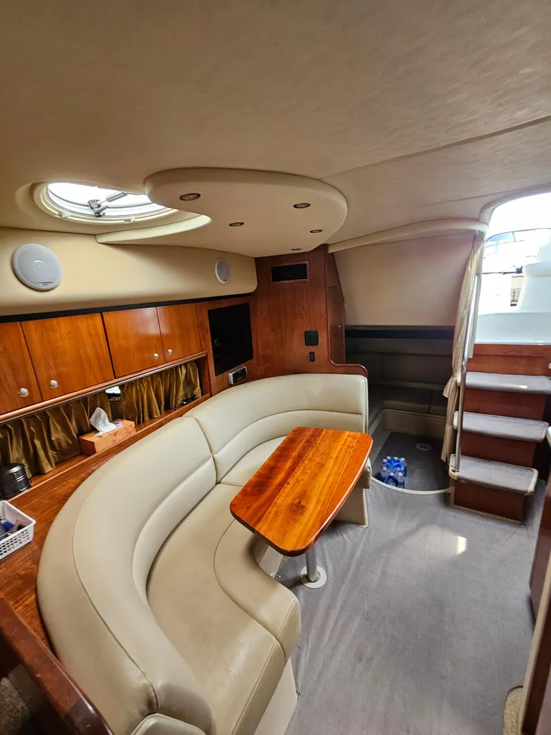 Slide: The Image of 2004 Cruisers Yachts 340 Express interior with curved seating and wooden table. - 34