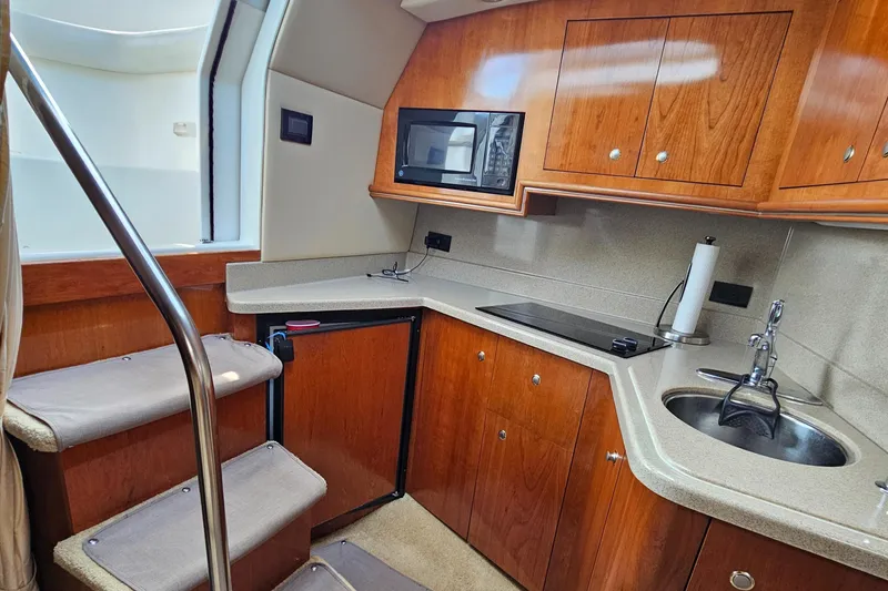 Slide: The Image of 2004 Cruisers Yachts 340 Express interior kitchen with wood cabinets, microwave, and sink. - 36