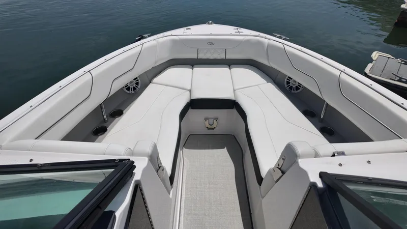 Slide: The Image of 2021 Regal LX6 boat interior with white seating and cup holders on calm water. - 19