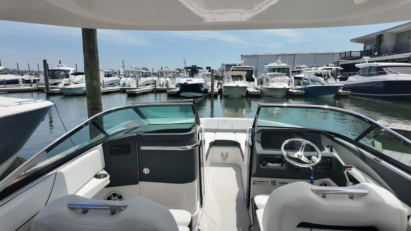 Slide: The Image of 2021 Regal LX6 boat interior at marina, surrounded by various docked boats. - 21