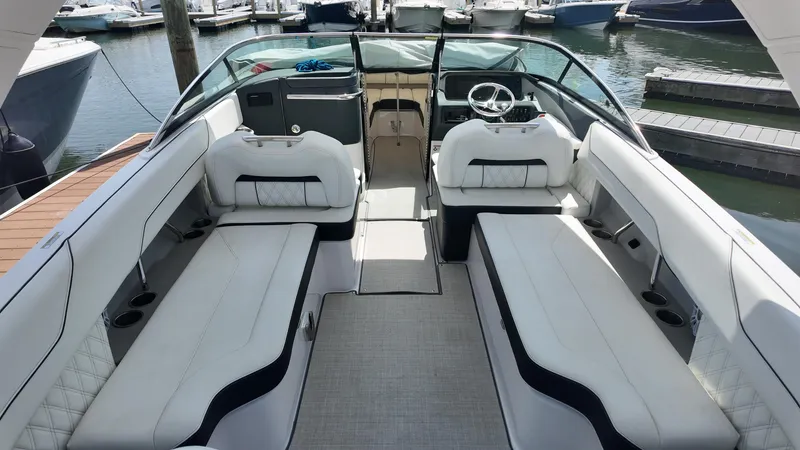 Slide: The Image of 2021 Regal LX6 boat interior with white seating, docked at a marina. - 6