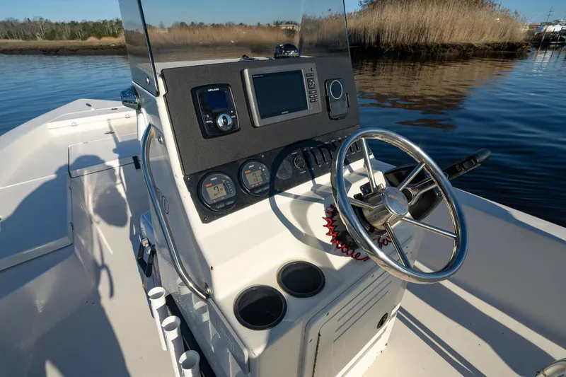 Slide: The Image of 2005 Pathfinder 2000v boat console with steering wheel and gauges on calm water. - 4