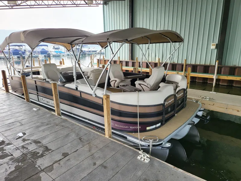 Slide: The Image of 2014 Premier 275 Boundary Waters pontoon boat docked under a covered marina. - 1