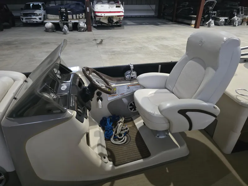 Slide: The Image of Captain's chair and helm of 2014 Premier 275 Boundary Waters pontoon boat in storage. - 44