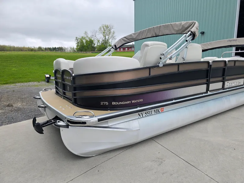 Slide: The Image of 2014 Premier 275 Boundary Waters pontoon boat parked on concrete near a green building. - 49